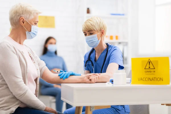 Enfermera que hace la inyección de la vacuna del Coronavirus a la señora mayor en el hospital — Foto de Stock