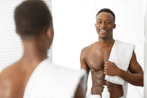 Hombre africano musculoso sin camisa sosteniendo la toalla de pie en baño moderno — Foto de Stock