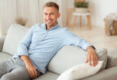Adam evinde kanepede dinleniyor.