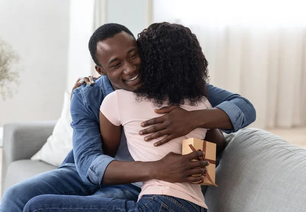 Glad afrikansk kille med närvarande kramar sin flickvän — Stockfoto