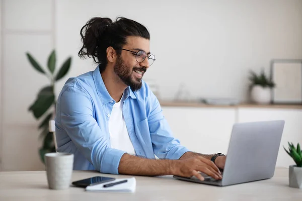 Lächelnder westlicher Freiberufler, der zu Hause im Büro am Laptop arbeitet — Stockfoto