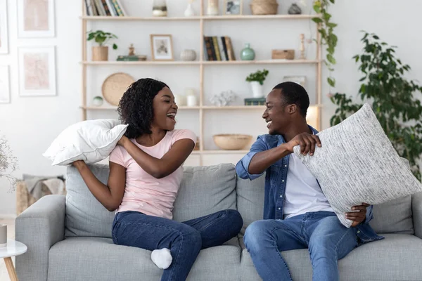Felice amorevole coppia nera lotta con cuscini in soggiorno — Foto Stock