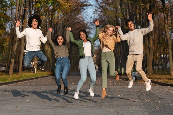 Безтурботні студенти з руками вгору стрибають в повітрі — стокове фото