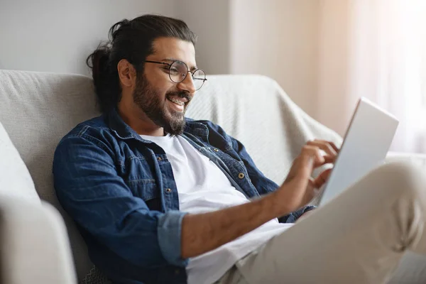 Homem ocidental feliz verificando as mídias sociais em tablet digital em casa — Fotografia de Stock