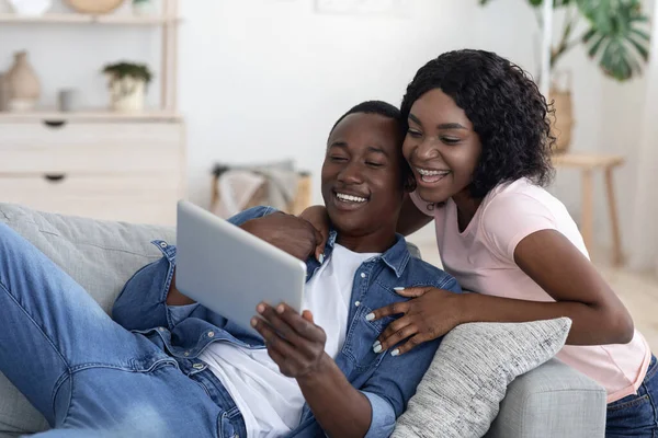 Casal negro alegre usando tablet digital em casa — Fotografia de Stock