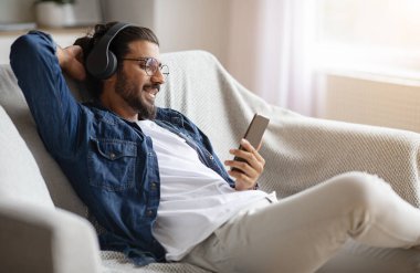 Rahat Hintli adam akıllı telefondan kablosuz kulaklıkla müzik dinlemekten hoşlanıyor.