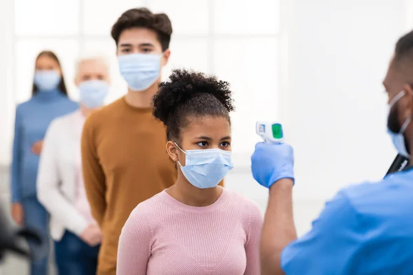 Enfermera midiendo fiebre para chica de pie en la cola en el hospital —  Fotos de Stock