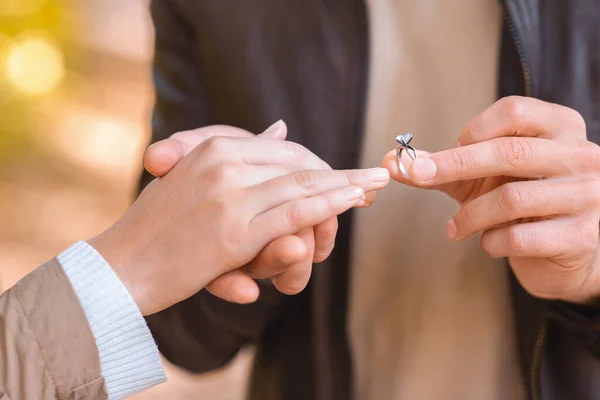 CLose up de hombre poniendo anillo en dedo femenino —  Fotos de Stock