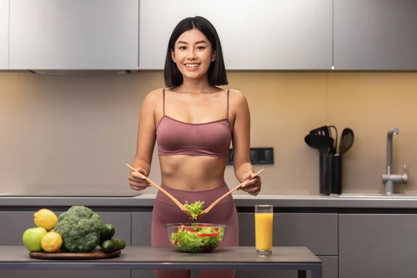 Apto asiático senhora cozinhar salada na cozinha, sorrindo para câmera — Fotografia de Stock