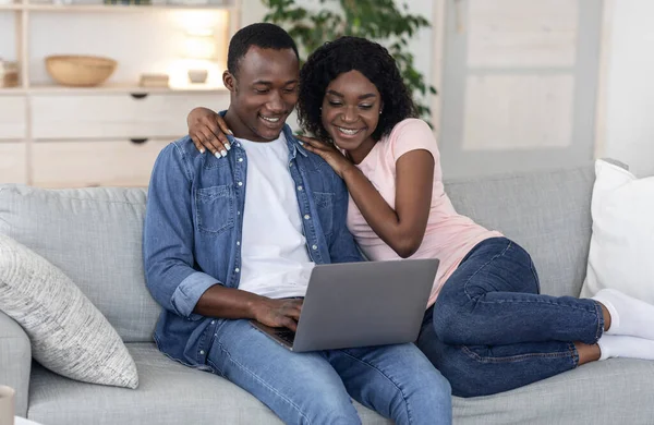Mutlu siyah çift evde dizüstü bilgisayar kullanıyor. — Stok fotoğraf