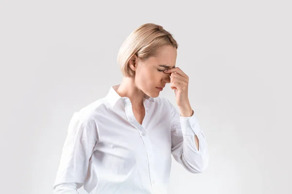 Cansado empregado corporativo feminino sofrendo de dor de cabeça no fundo do estúdio cinza claro — Fotografia de Stock
