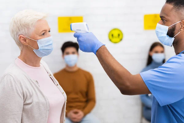 Médico que mide la temperatura para la señora mayor Paciente antes de la cita en interiores —  Fotos de Stock