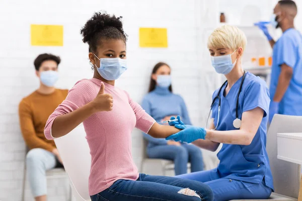 Happy Vaccinated Girl Gesturing Thumbs-Up após a vacina Covid-19 no hospital — Fotografia de Stock