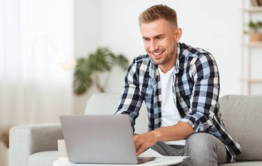 Koltukta dizüstü bilgisayar kullanan mutlu bir adam.