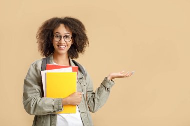Başarılı genç bir öğrenci. Gözlüklü Afrikalı Amerikalı kadın not defteri tutuyor ve boş bir alanı işaret ediyor.
