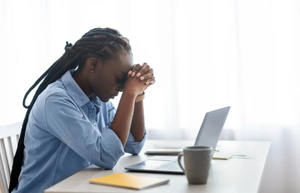 Geschäftliche Probleme. Depressive schwarze Geschäftsfrau sitzt am Arbeitsplatz im Büro und berührt den Kopf — Stockfoto