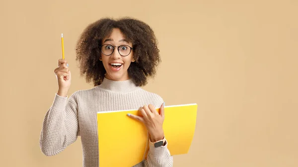 Great idea for education or training project. Surprise african american woman in glasses, with open mouth and notepad, raises pencil up — Stock Photo, Image