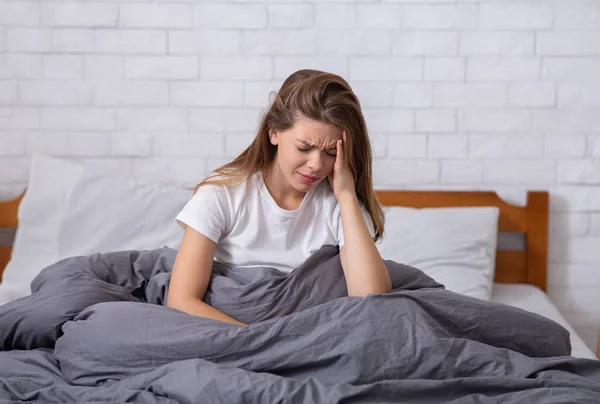 Boldogtalan fiatal nő szenved depresszió vagy álmatlanság, amelynek szörnyű fejfájás, elárasztották a negatív gondolatok — Stock Fotó