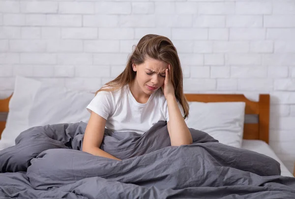 Unglückliche junge Frau, die unter Depressionen oder Schlaflosigkeit leidet, schreckliche Kopfschmerzen hat und von negativen Gedanken überwältigt wird — Stockfoto