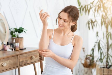 Mutlu genç bayan havluya sarılıp dirseğini nemlendiriyor.