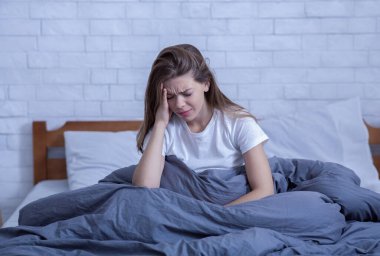 Yalnız ve stresli bir kadın, depresyon ya da migrenden muzdarip. Travma sonrası stres bozukluğu yüzünden uykusuzluk çekiyor.
