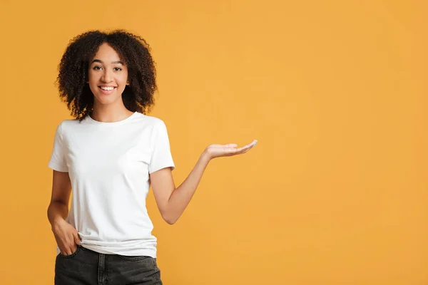 La mejor oferta, emociones de la gente y estilo de vida. Señora afroamericana sonriente confiada que usa en puntos blancos de la camiseta con la mano al espacio libre — Foto de Stock