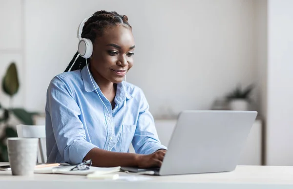 Millennial Negro Empleada Trabajar con el ordenador portátil y escuchar música en la oficina — Foto de Stock