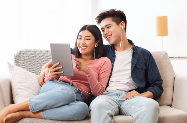 Veselý asijské pár pomocí digitální tablet procházení internetu doma — Stock fotografie
