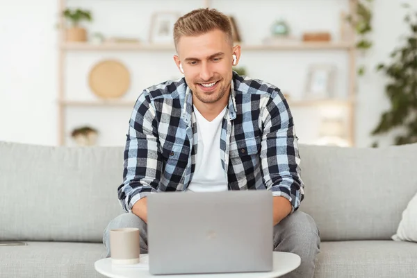 Hombre escuchando música en línea en los auriculares, utilizando el ordenador portátil — Foto de Stock