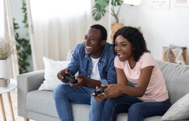Neşeli Afrikalı Amerikalı çift evde video oyunu oynuyor.