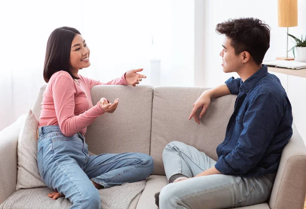 Wesoła para Flirtuje i rozmawia siedząc na kanapie w domu — Zdjęcie stockowe
