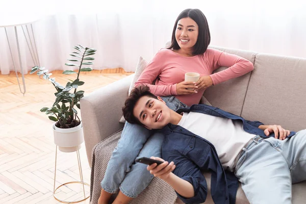 Casal japonês assistindo TV desfrutando de filmes familiares relaxando em casa — Fotografia de Stock