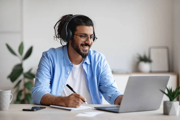 Uczenie się na odległość. Indian Guy oglądanie webinarium na laptopie i notatki — Zdjęcie stockowe