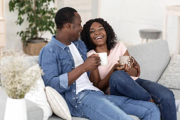 Amantes negros tomando té y riéndose en casa —  Fotos de Stock