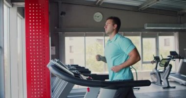 Kardiyo çalışması, spor salonunda koşu bandında egzersiz yapan adam, yan görüş, yavaş çekim.