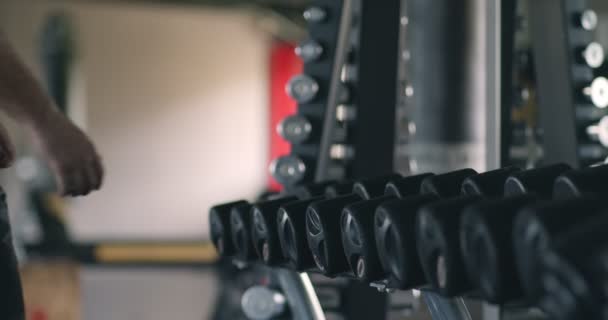 Gros plan de l'homme en surpoids prenant haltères de rack à la salle de gym, au ralenti — Video