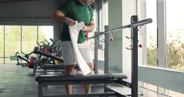 Мужчина кладет полотенце на барную стойку перед тренировкой, персональная гигиена концепции — стоковое видео