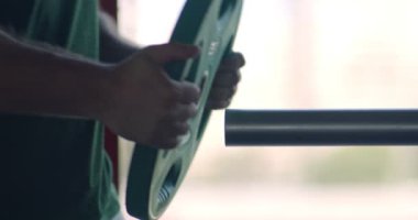 Sporcu halterine ağırlık plakası ekliyor, spor salonundaki antrenmanına hazırlanıyor, kapat.