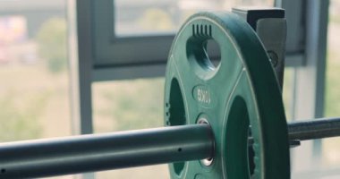 Sporcu spor salonunda egzersiz yapmadan önce halterlere ağırlık plakası ekliyor. Kapatın.