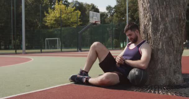 Молодой баскетболист проверяет свою активность на умных часах — стоковое видео