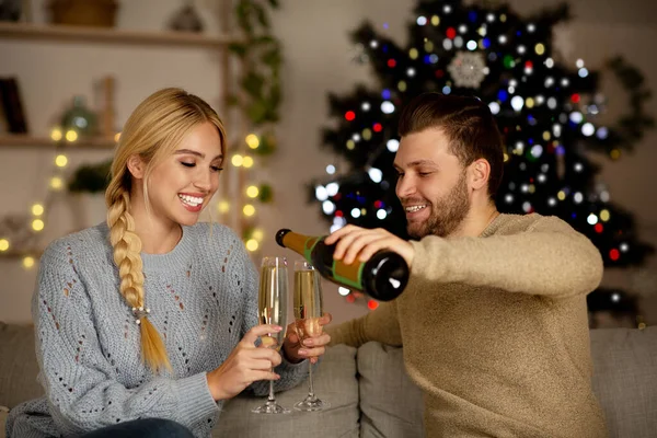 Pareja joven bebiendo champán, celebrando el Año Nuevo juntos en casa — Foto de Stock