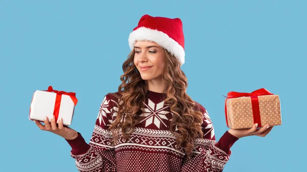 Shopping per vacanze invernali. Attraente giovane donna in abito di Natale in possesso di due scatole regalo su sfondo blu studio — Foto Stock