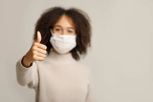 코로나 바이러스와 독감으로부터 보호 한다. 보호용 마스크를 쓴 젊은 아프리카계 미국인 여성의 엄지에 집중하 세요. — 스톡 사진