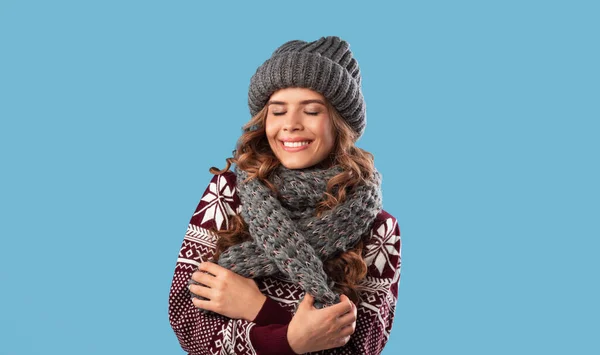 Moda de inverno. Mulher bonita usando camisola de lã, chapéu de gorro de malha e cachecol no fundo do estúdio azul — Fotografia de Stock