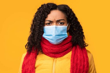 Yüzü maskeli Afrikalı Kadın Kamera, Sarı Arkaplan