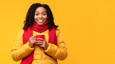 Ceketli Afrikalı kadın sarı arka planda kahve pozu veriyor.