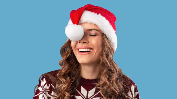 Retrato de una joven tonta en ropa de abrigo divirtiéndose con el sombrero de Santa sobre fondo de estudio azul, panorama — Foto de Stock