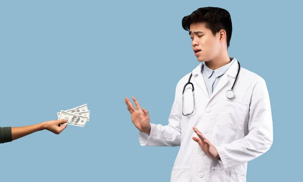 Vyděšený asijský lékař odmítá úplatek od pacientky — Stock fotografie