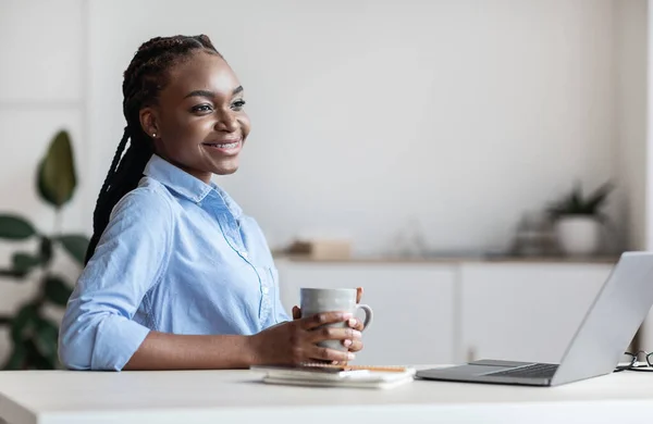 Ονειρεμένη νεαρή μαύρη πολυάσχολη κυρία που κάνει διάλειμμα για καφέ στο χώρο εργασίας στο γραφείο — Φωτογραφία Αρχείου