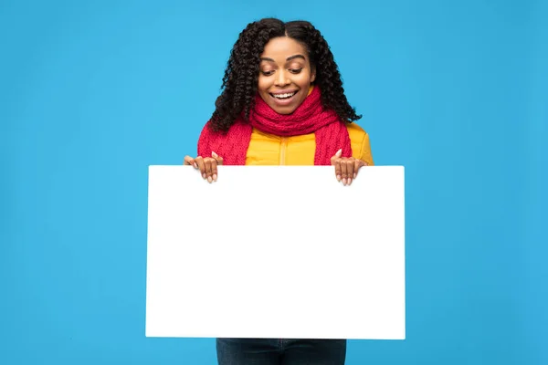 Μαύρη Millennial γυναίκα κρατώντας κενό αφίσας στέκεται πάνω από το μπλε φόντο — Φωτογραφία Αρχείου